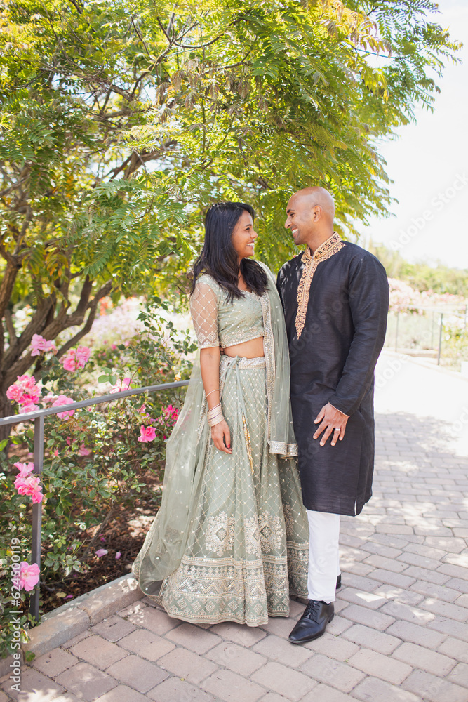 beautiful indian couple hugging in close with a bindi and traditional sari dress and kurta in a garden with flowers beautiful indian couple hugging in close with a bindi and traditional sari dress and kurta in a garden with flowers