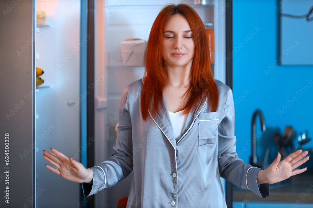 Young woman near open fridge in kitchen at night
