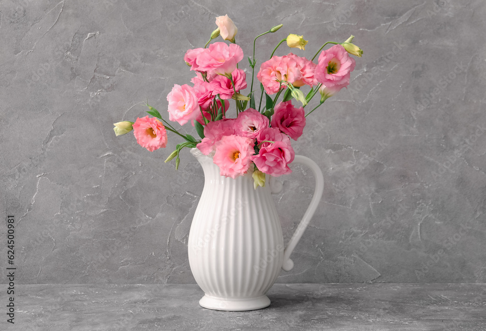 Jug with beautiful pink eustoma flowers on grey background Jug with beautiful pink eustoma flowers on grey background
