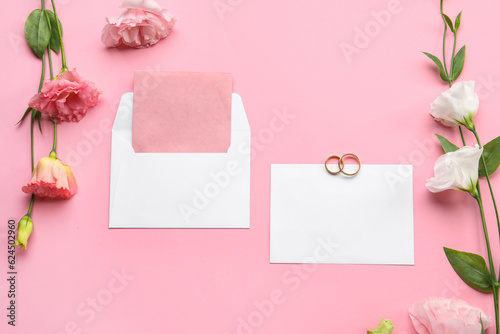 Composition with blank cards, envelope, wedding rings and beautiful eustoma flowers on pink background © Pixel-Shot