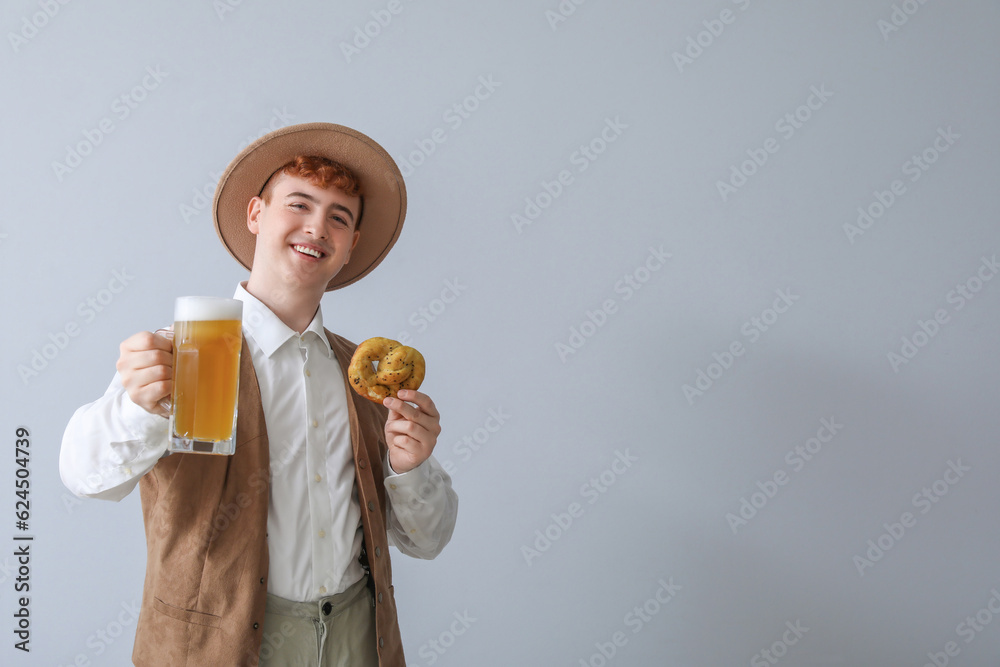 Young man in traditional German clothes with beer and pretzel on light background Young man in traditional German clothes with beer and pretzel on light background