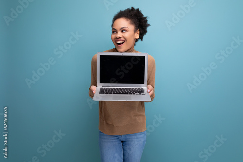 successful young female student with dark skin and fluffy hair demonstrates a project on a laptop screen on an isolated background with copy space