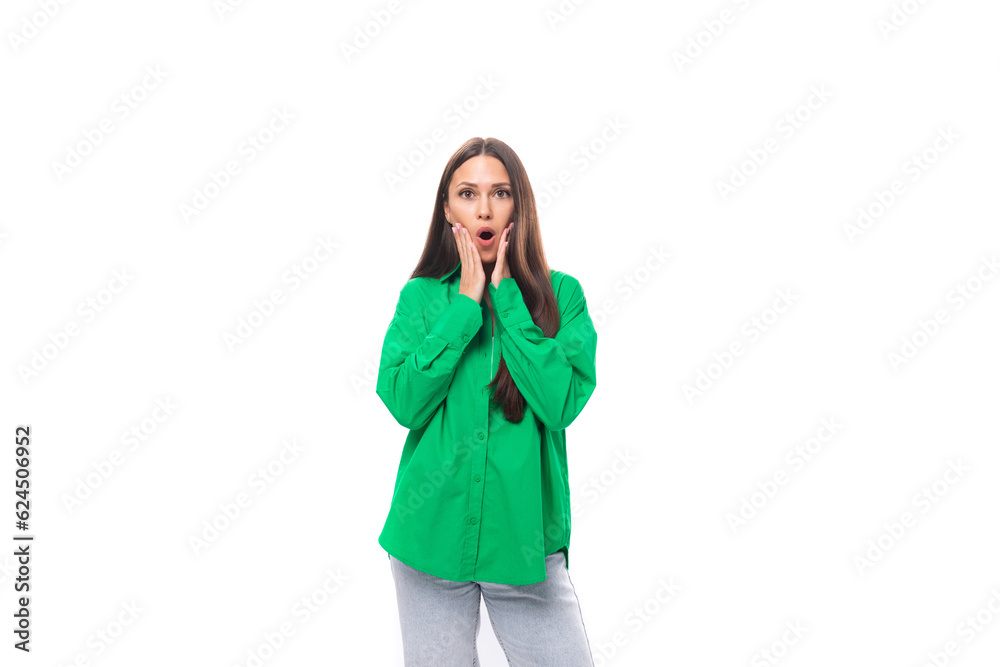 young brown-haired female model with brown eyes in a green shirt is surprised on a white background with copy space for text young brown-haired female model with brown eyes in a green shirt is surprised on a white background with copy space for text