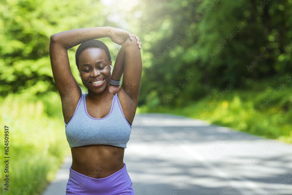 Portrait of a sporty young woman stretching her arms while exercising outdoors.