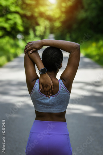 Portrait of a sporty young woman stretching her arms while exercising outdoors.