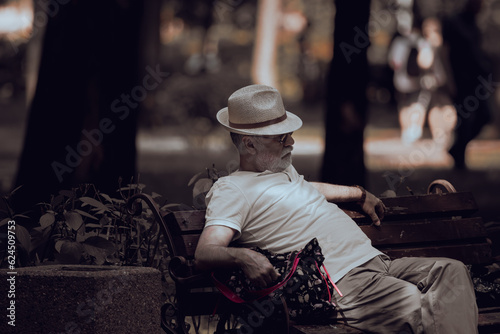 Stylish man in white. White. Gray beard. White hat. Peaceful old age. Old parents. Noble gray hair. A man on a bench. © Larysa