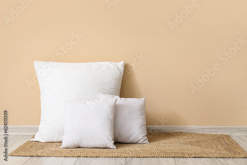 Fototapeta Naklejka Na Ścianę i Meble -  White pillows on wicker mat near beige wall