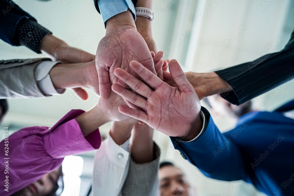 Business team stacking hands as symbol of unity Business team stacking hands as symbol of unity