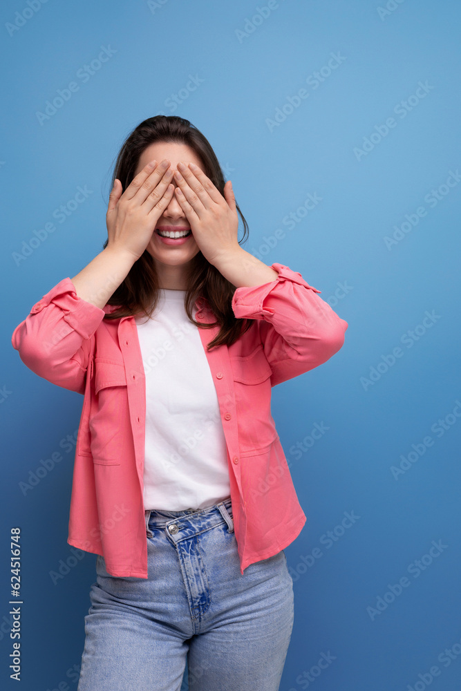 smiling brunette woman with hair below her shoulders in a shirt closed her hands in anticipation of a surprise smiling brunette woman with hair below her shoulders in a shirt closed her hands in anticipation of a surprise