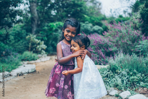 Canvas Print beautiful indian sisters girls hugging in the park with trees and greenery