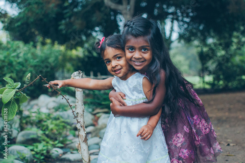 Photography beautiful indian sisters girls hugging in the park with trees and greenery
