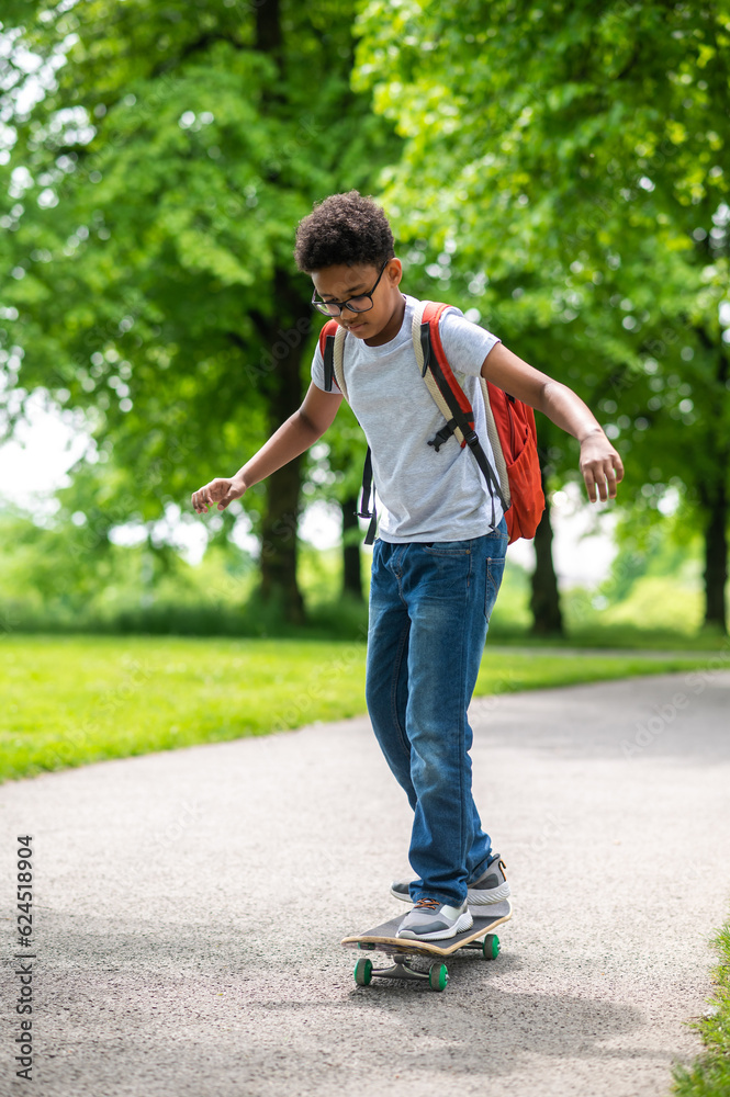 A curly-haired boy on a longboard in the park