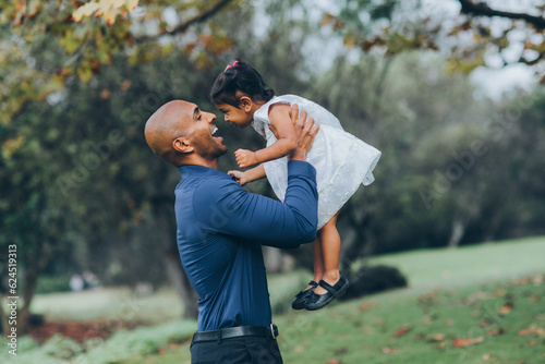 Photography beautiful indian father playfully hugging his child daughter girl in the park wi