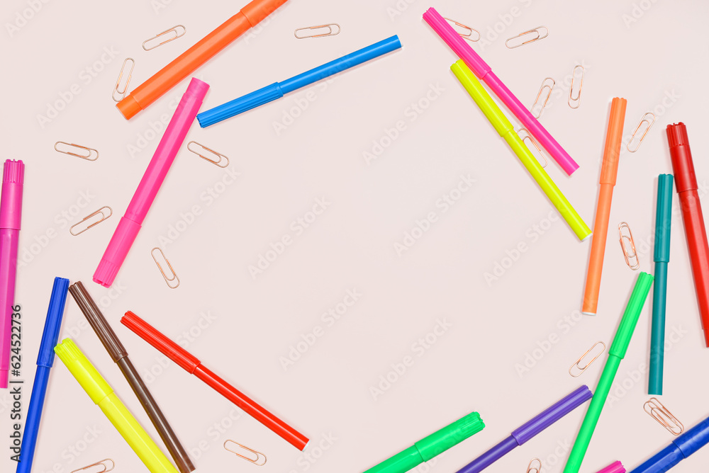Frame made of colorful felt-tip pens and paperclips on pink background Frame made of colorful felt-tip pens and paperclips on pink background