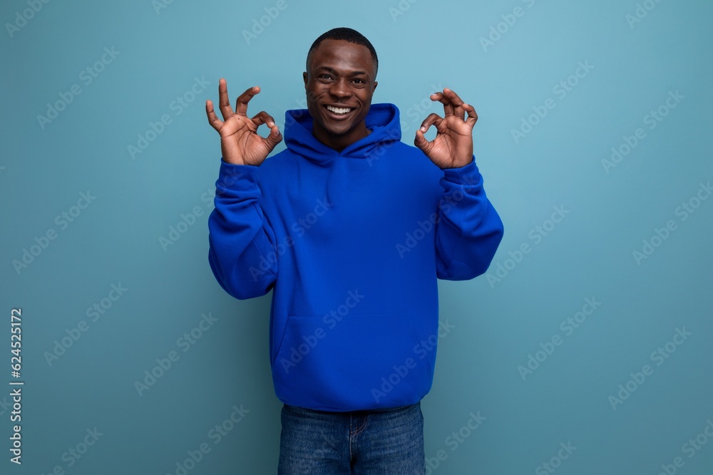 Naklejka premium portrait of a 30s black African man in a hooded sweatshirt laughing at his stupidity in a studio background with copy space