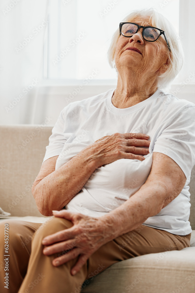 Elderly woman severe chest pain sitting on the sofa, health problems in