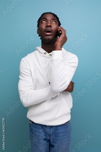 smiling young african guy in a white sweatshirt chatting on the phone © Ivan Traimak