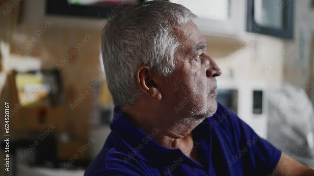 Sad depressed unshaven senior lost in thought at home staring out home window in quiet despair Sad depressed unshaven senior lost in thought at home staring out home window in quiet despair