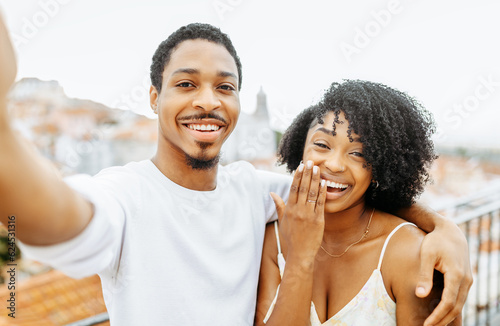 Laughing young african american man hug lady, show ring, taking selfie, enjoy date and engagement