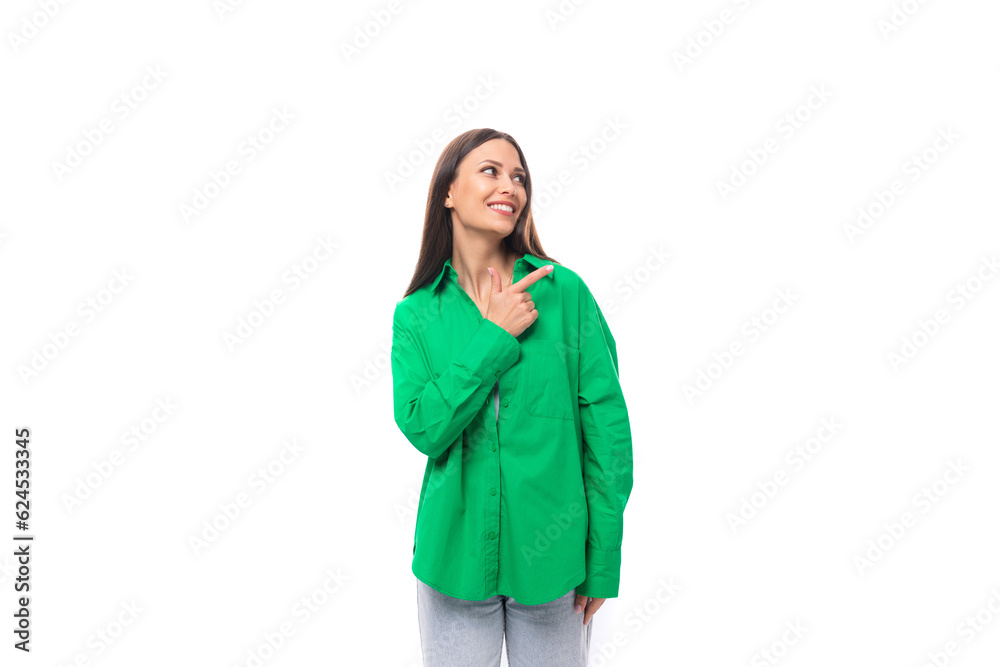 young caucasian brunette lady with make-up dressed in an elegant green shirt points with her hands towards the wall with empty space young caucasian brunette lady with make-up dressed in an elegant green shirt points with her hands towards the wall with empty space