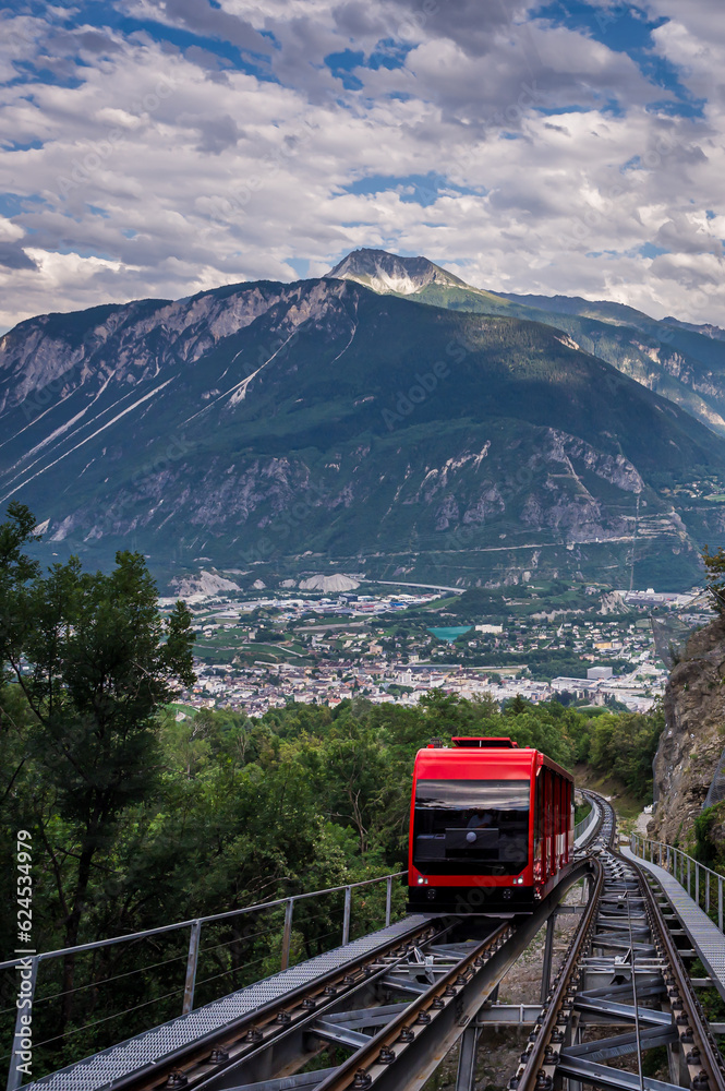Red Swiss funicular in Switzerland. Cable car with view over Sierre city and mountain.
