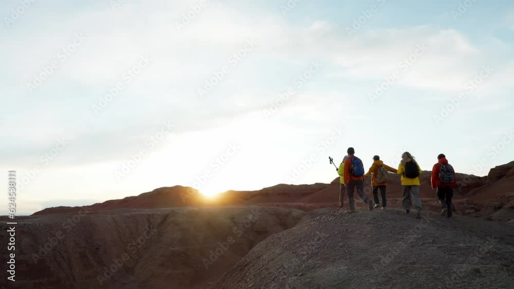 Travel group stand on mountain peak and raise arms in sunset. Achievement joy, success, victory and motivation top on high wilderness area back view Travel group stand on mountain peak and raise arms in sunset. Achievement joy, success, victory and motivation top on high wilderness area back view