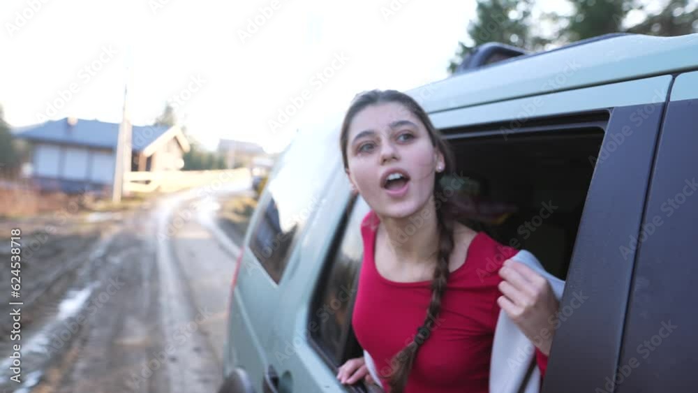 Car road trip. Happy beautiful woman looks out of the open window in wonder of holiday travel Car road trip. Happy beautiful woman looks out of the open window in wonder of holiday travel