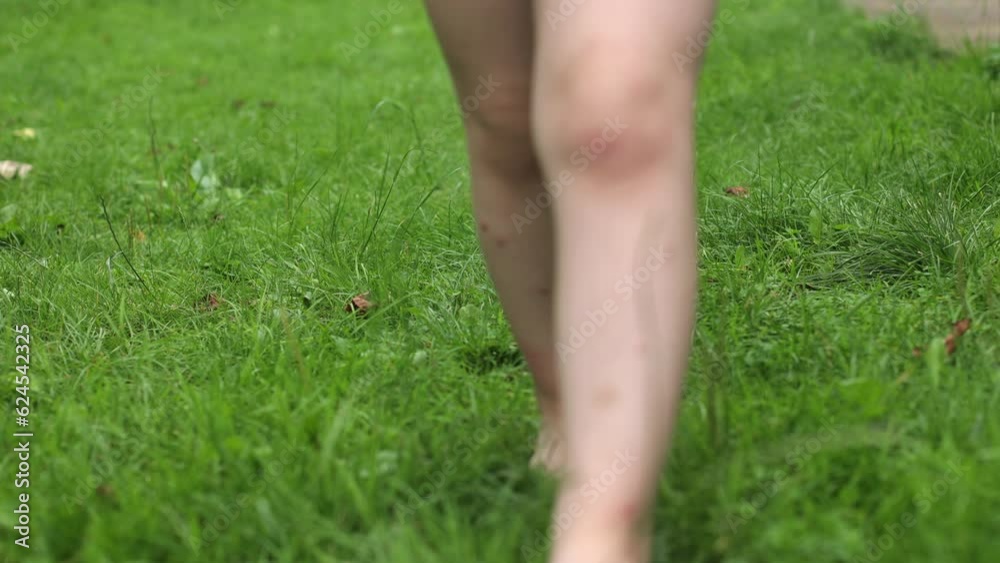 A little girl with bare feet on the grass. Sandals in the summer, hot summer and rest. Green grass, for children, lawn near the house. The little one likes to walk barefoot on the grass. A little girl with bare feet on the grass. Sandals in the summer, hot summer and rest. Green grass, for children, lawn near the house. The little one likes to walk barefoot on the grass.