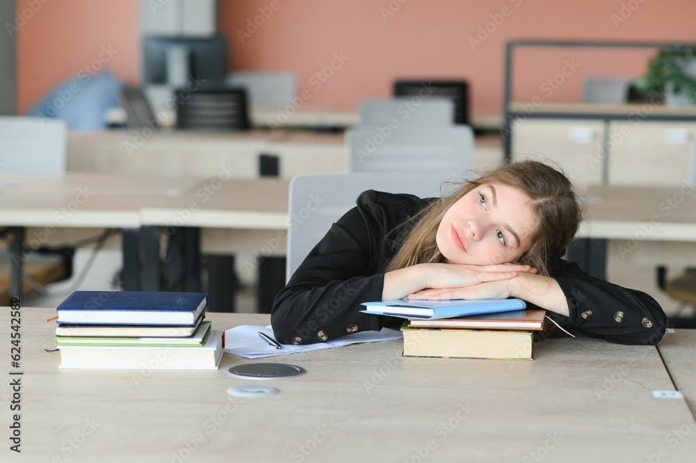 Teen girl studying with textbook writing essay learning in classroom. Teen girl studying with textbook writing essay learning in classroom.