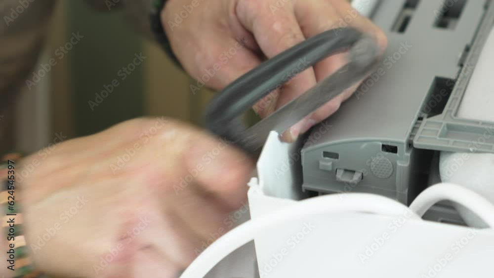The repairman saws a hole in the body of the split system for laying wires The repairman saws a hole in the body of the split system for laying wires