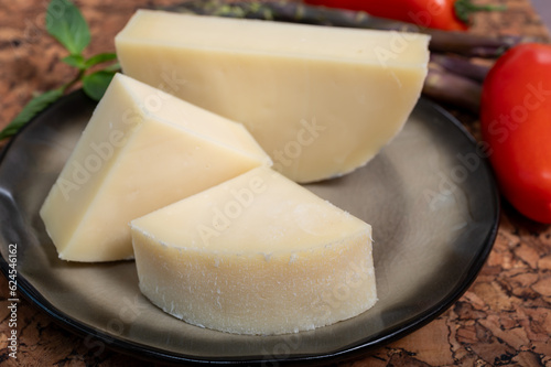 Italian cheese, Provolone dolce cow cheese from Cremona served with olive bread and tomatoes close up photo