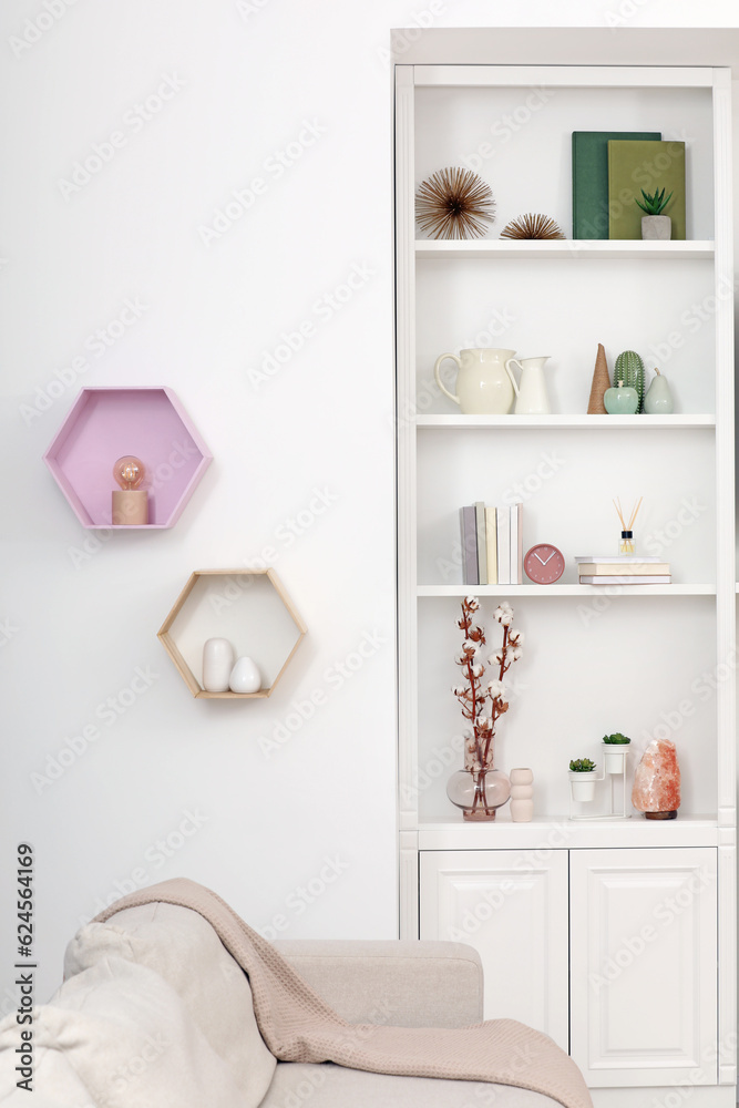 Fototapeta premium Stylish shelves with decorative elements and sofa. Interior design