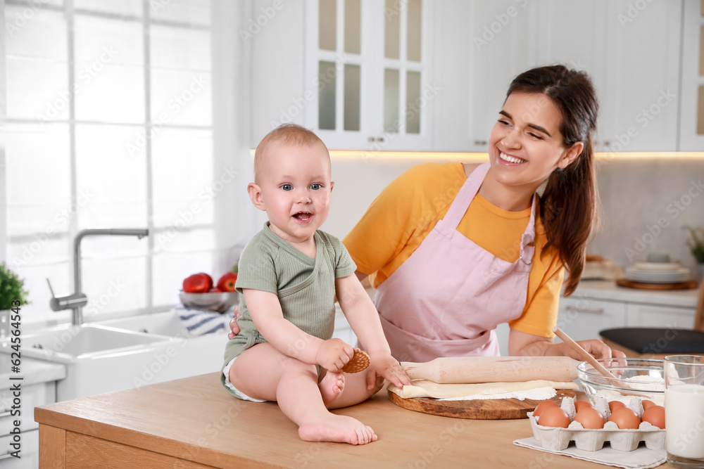 Happy young woman and her cute little baby cooking together in kitchen Happy young woman and her cute little baby cooking together in kitchen