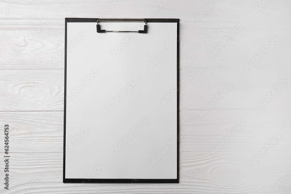 New clipboard with sheet of blank paper on white wooden table, top view. Space for text