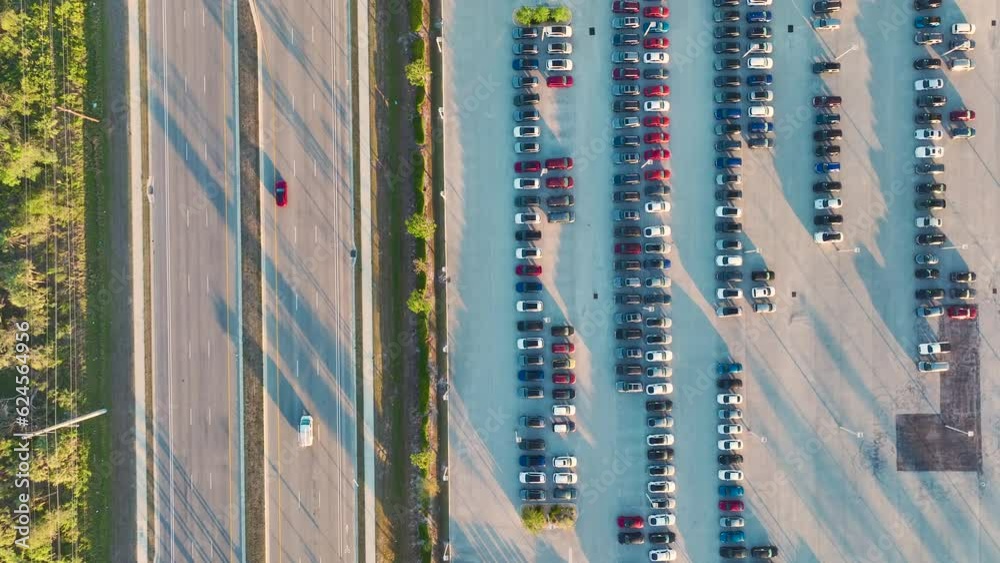 Aerial view of dealership parking lot with many brand new cars for sale near wide american highway. Development of US automotive industry concept Aerial view of dealership parking lot with many brand new cars for sale near wide american highway. Development of US automotive industry concept