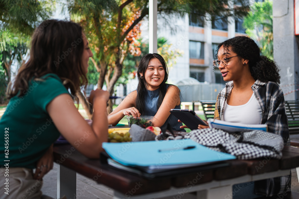 © Pablo Rasero - Three student friends talking to each other while they are studying for an exam.