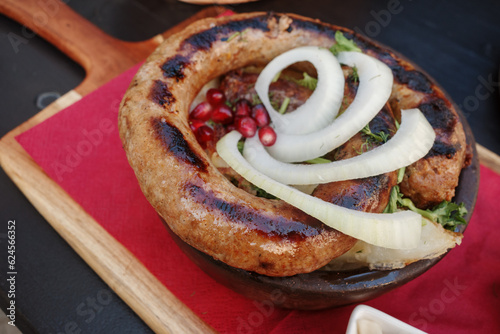 Top view, curl of Kupati,  Georgian spicy sausage with distinct flavor, on top with onion and barberry. photo