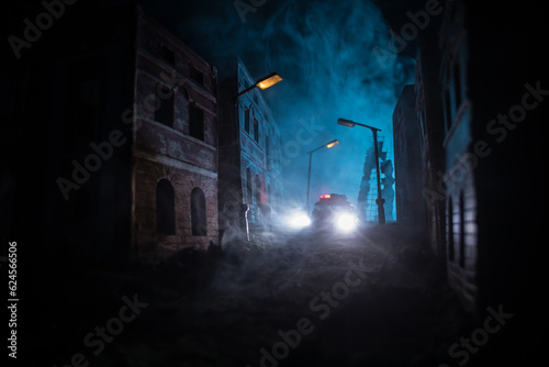 Police raid at night and you are under arrest concept. Silhouette of handcuffs with police car on backside. Image with the flashing red and blue police lights at foggy background. Slider shot photo