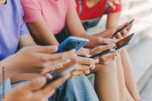 Closeup, group of teenagers holding mobile phones watching video, communication online, chatting, selective focus. Technology, social media concept   © Maria Vitkovska