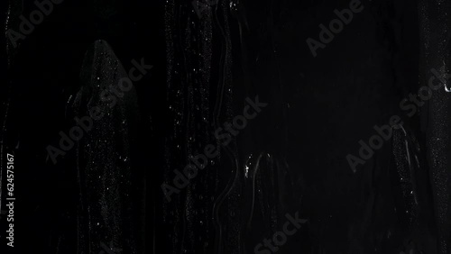 Water washing away droplets on a windowwater on glass window on a black background