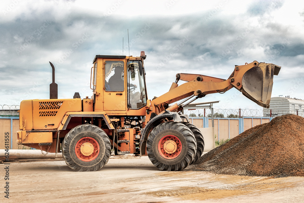 Powerful wheel loader or bulldozer at the construction site. Loader transports sand in a storage bucket. Powerful modern equipment for earthworks and bulk handling. Powerful wheel loader or bulldozer at the construction site. Loader transports sand in a storage bucket. Powerful modern equipment for earthworks and bulk handling.