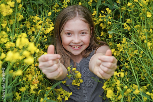 Bild auf Leinwand Cute little girl lie in yellow meadow and grass