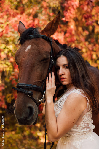 Beautiful, the bride in a white dress hugs a horse. Autumn wedding in nature 