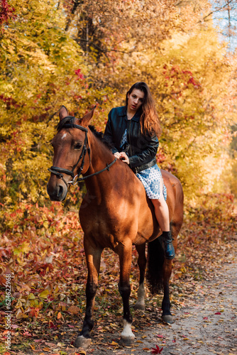Beautiful young woman posing on a horse in a beautiful autumn forest