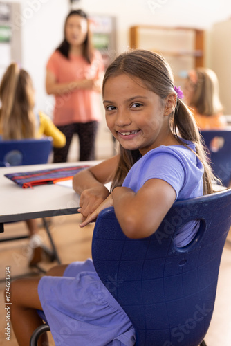 Portrait of happy caucasian schoolgirl in diverse elementary school class