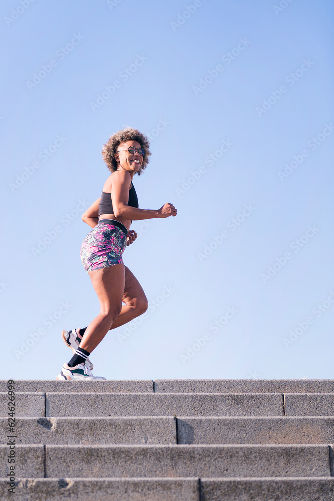vertical photo of a happy african american woman running outdoors in a urban landscape, concept of sports and active lifestyle, copy space for text vertical photo of a happy african american woman running outdoors in a urban landscape, concept of sports and active lifestyle, copy space for text