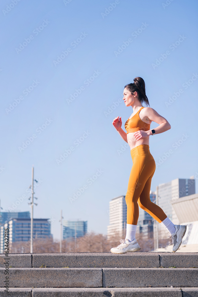 vertical photo of a caucasian sports woman running outdoors in a urban landscape, concept of sport and active lifestyle, copy space for text