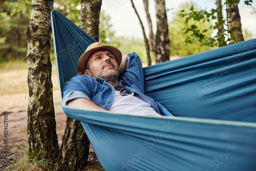 Adult man relaxing in hammock in forest