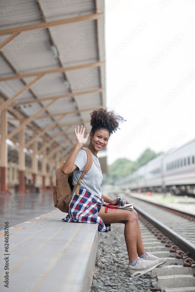 Young woman female smiling traveler with back pack looking to map while waiting for the train at train station. High quality photo Young woman female smiling traveler with back pack looking to map while waiting for the train at train station. High quality photo