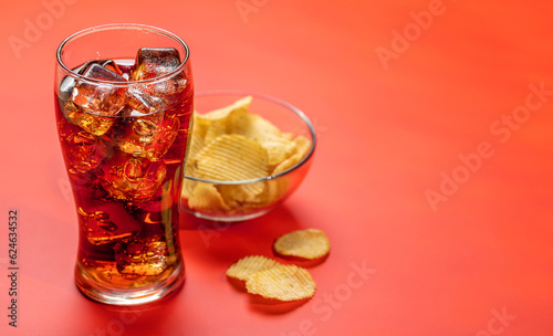 Refreshing glass of cola with ice  accompanied by a serving of crispy chips